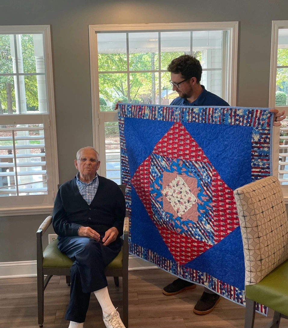 Interim Healthcare hospice program coordinator presenting hospice patient and veteran Grady Stewart with a Quilt of Valor